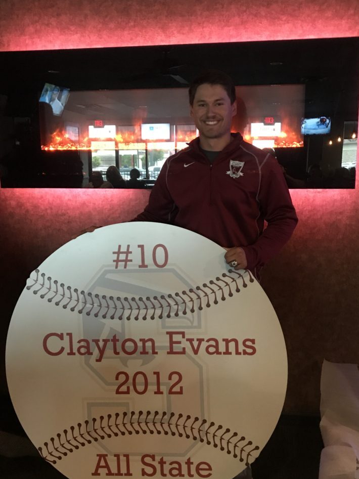 Man posing with a large baseball plaque honoring Clayton Evans from 2012.