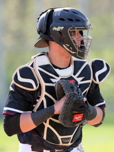 Baseball catcher in full gear preparing to catch a pitch.
