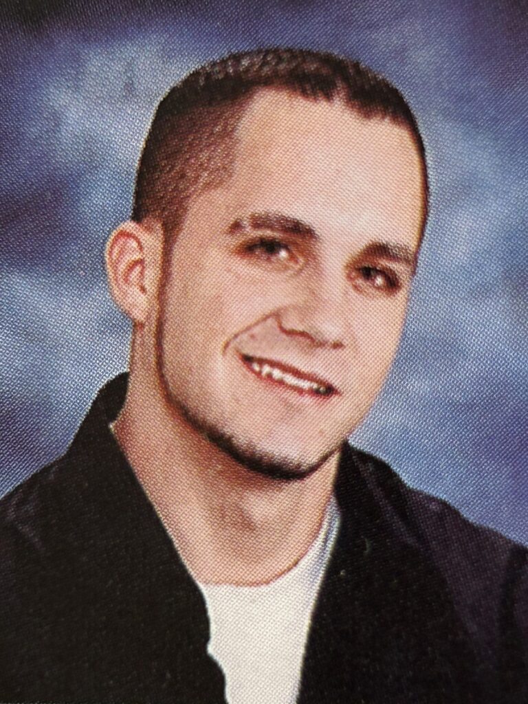 A young man with a short haircut and a small goatee smiling.